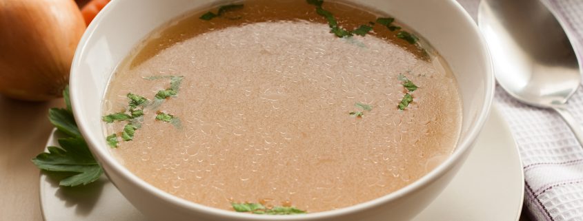 Bone broth made from chicken served in a bowl with parsley