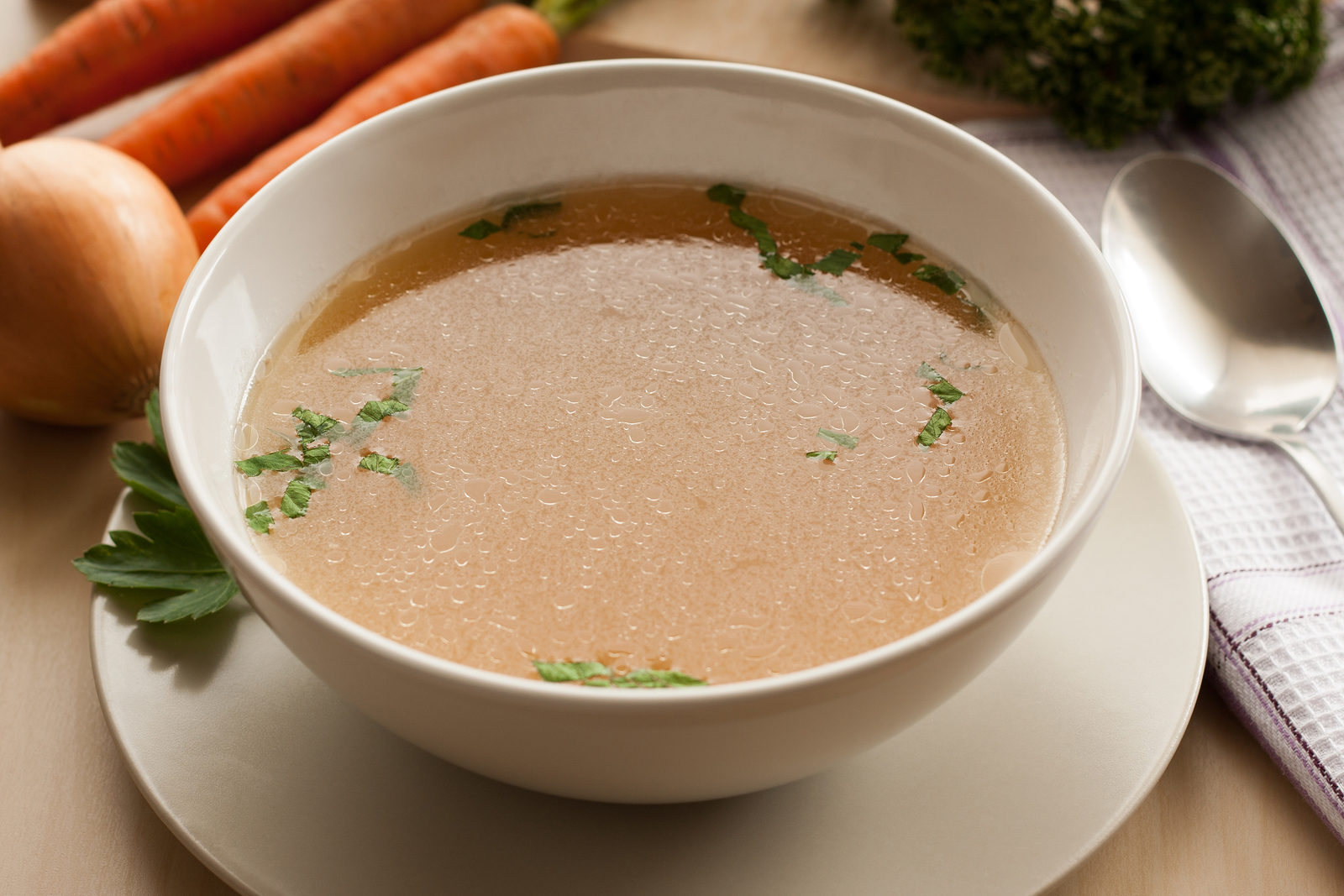 Bone broth made from chicken served in a bowl with parsley